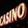 Brightly illuminated letters spell out 'CASINO' with glowing yellow bulbs and red outlines against a dark background.