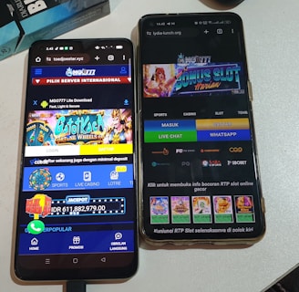 Two smartphones are displayed on a white surface, both showing gambling websites with colorful graphics, text, and various options for logging in and accessing games. The screens are bright and filled with promotional content related to casino and slot games.